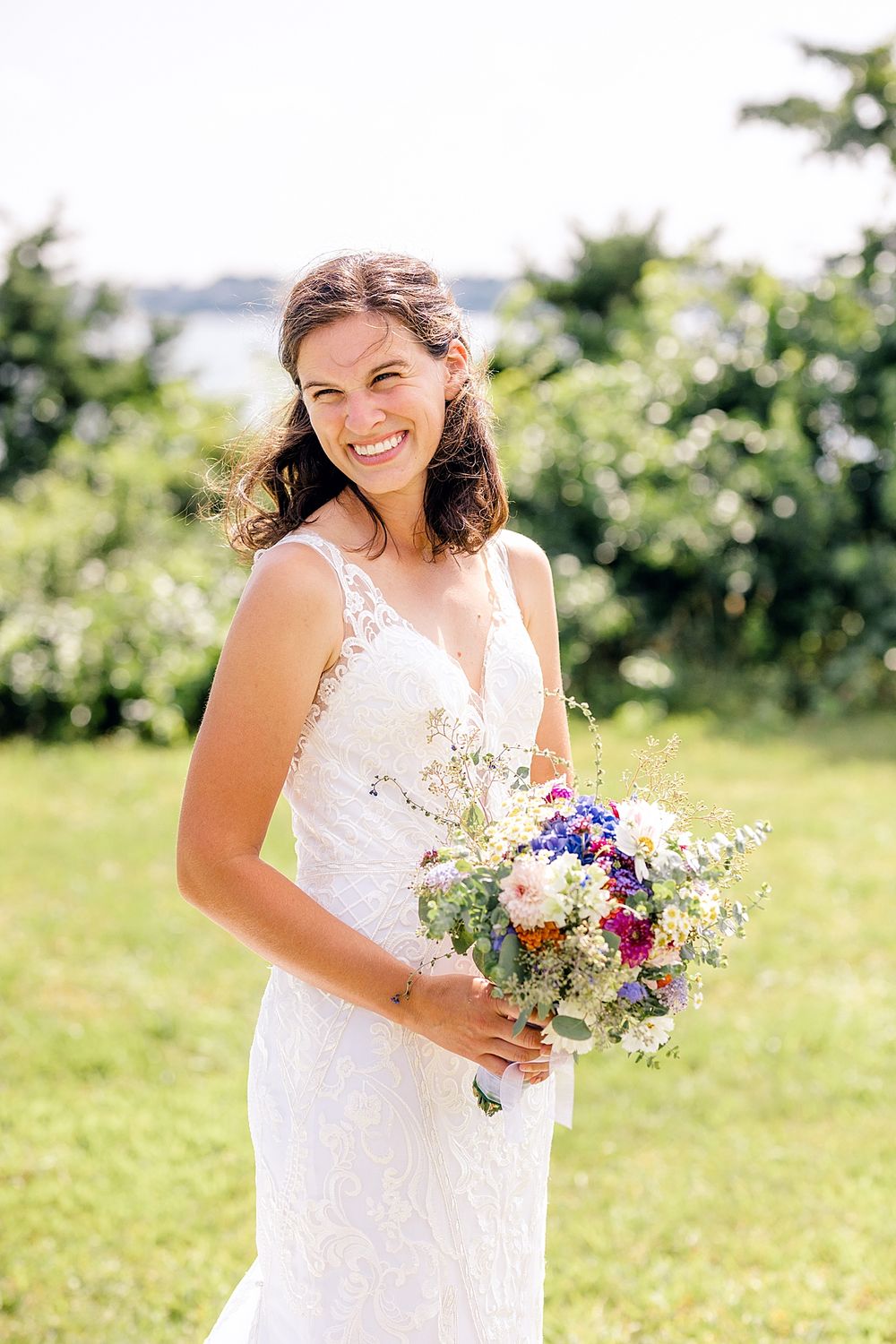 A stunning portrait of someone in a lace wedding dress holding a colorful wildflower bouquet.