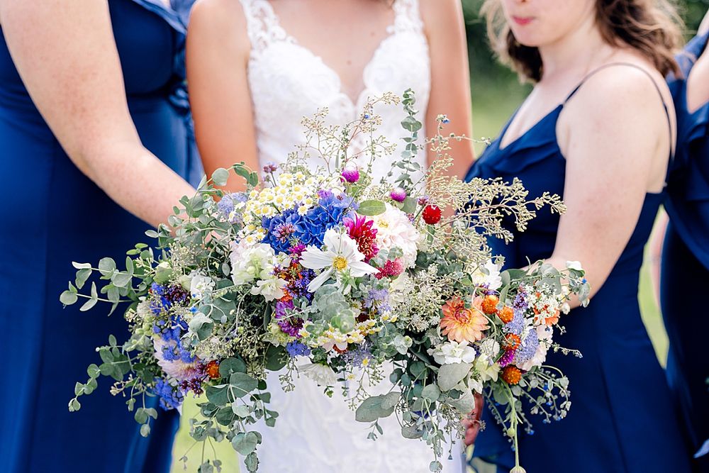 Close up of wedding bouquets featuring blue, white and pink flowers with eucalyptus greenery.