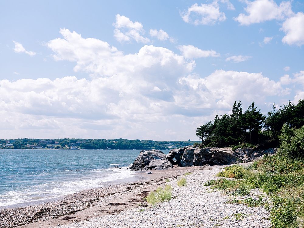 Rocky beach coastline with blue water and cloudy sky in summer.