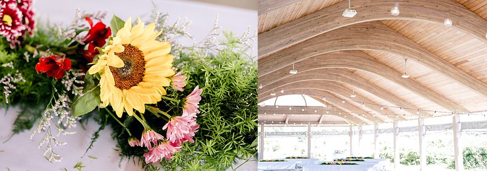 Sunflower and pink floral arrangements next to wooden beamed ceiling in event space.