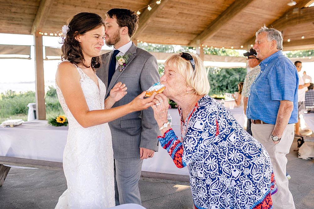 Wedding celebration under wooden pavilion with guests in blue floral dresses.