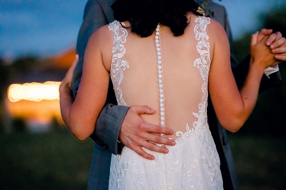 Close-up detail of a lace wedding dress back with buttons and sheer details.