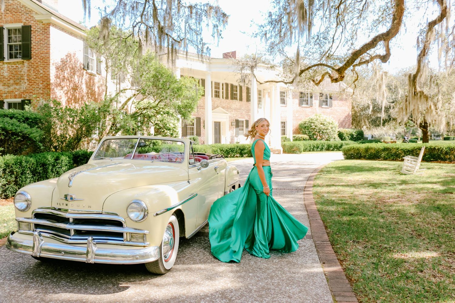 Vintage Plymouth convertible parked in front of a Southern mansion with Spanish moss draped trees.