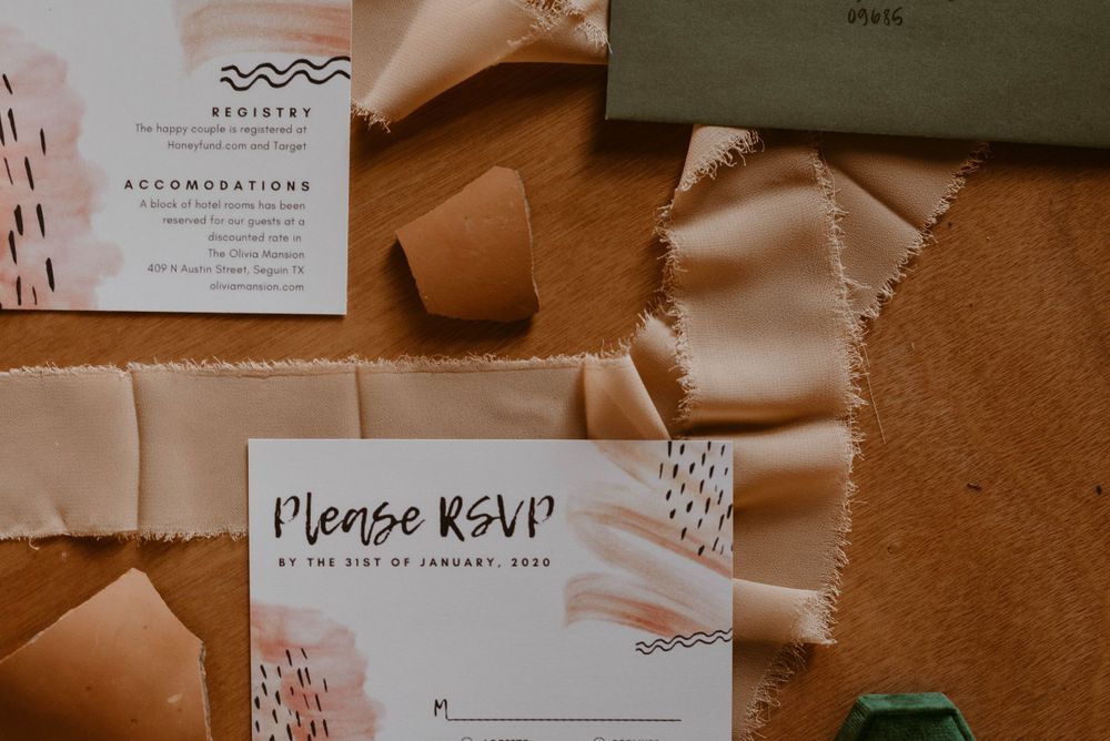 Modern wedding RSVP cards with abstract designs and ribbon details on brown paper.