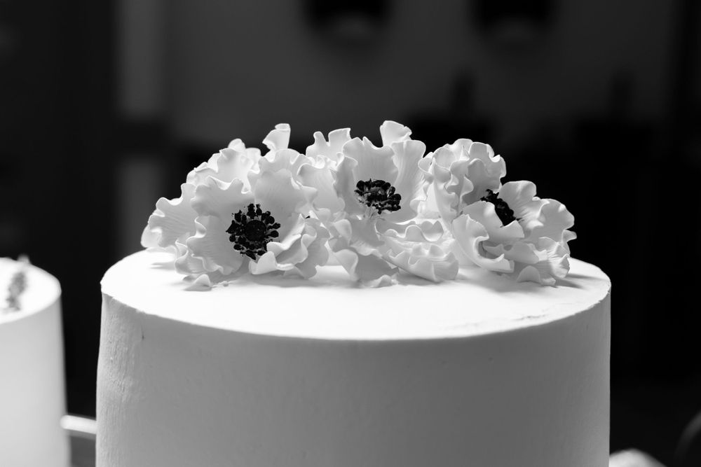 White wedding cake decorated with delicate sugar flowers in black and white photography.