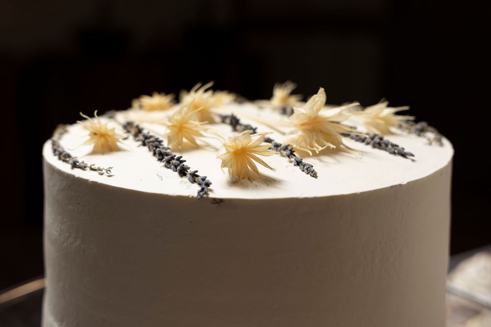 Modern white cake decorated with gold wheat stalks and black seed details.