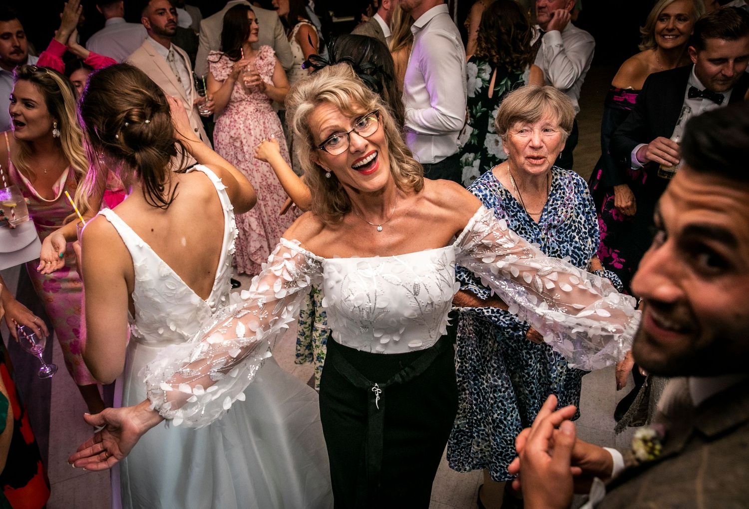 Wedding reception guests dancing and celebrating with joyful expressions.