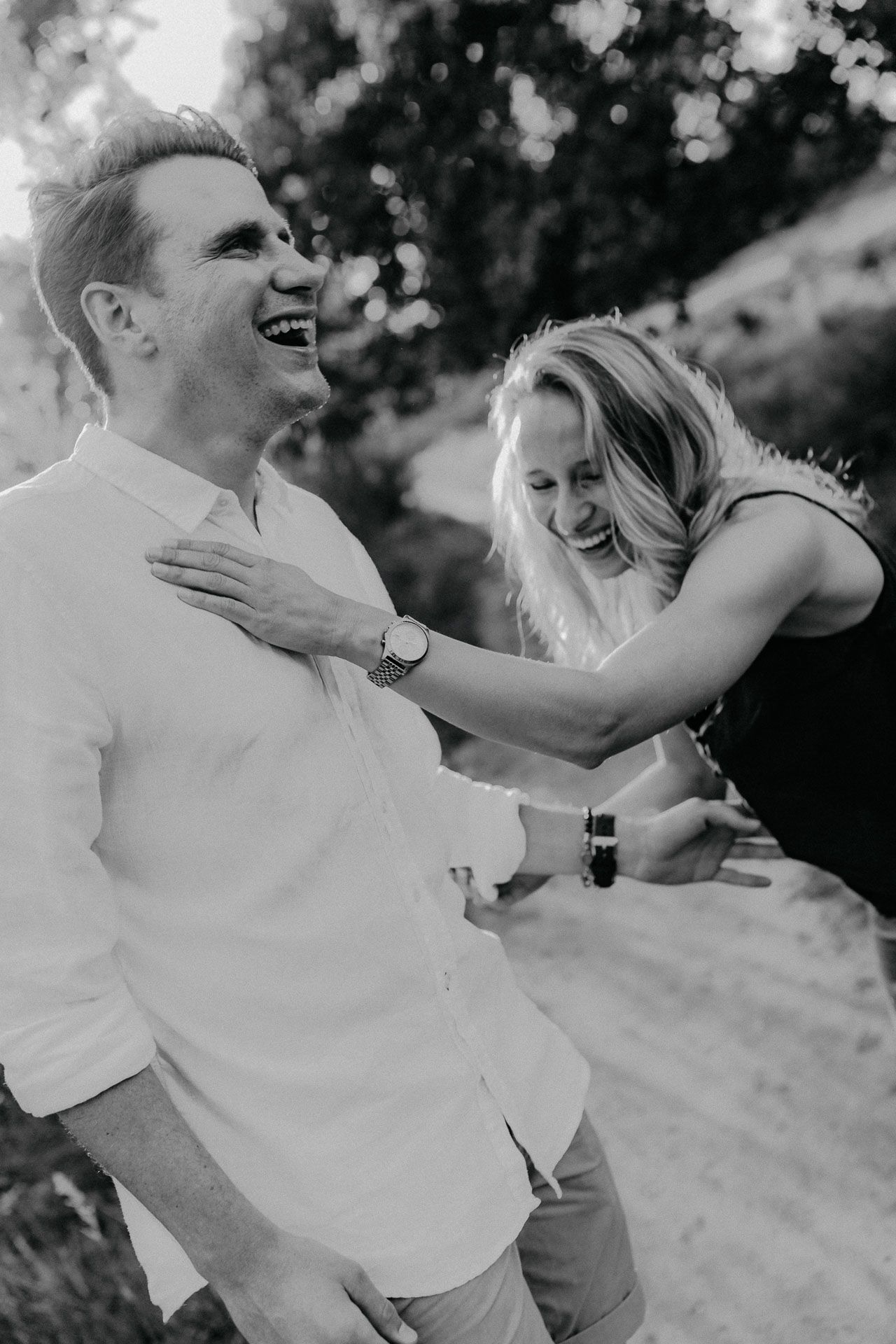 A joyful moment captured in black and white of a couple laughing together outdoors.