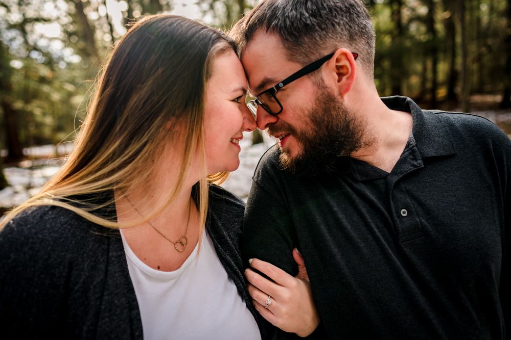 Romantic close-up shots of couple sharing intimate moments during winter forest engagement session.