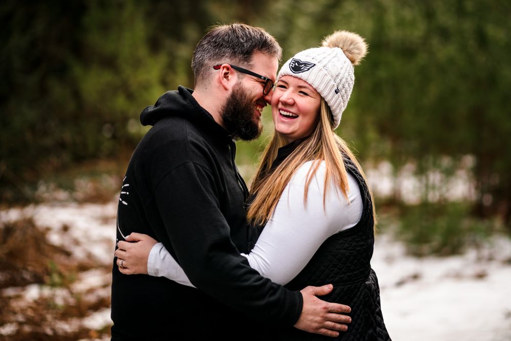 Playful couple's portrait session in a snowy winter setting.