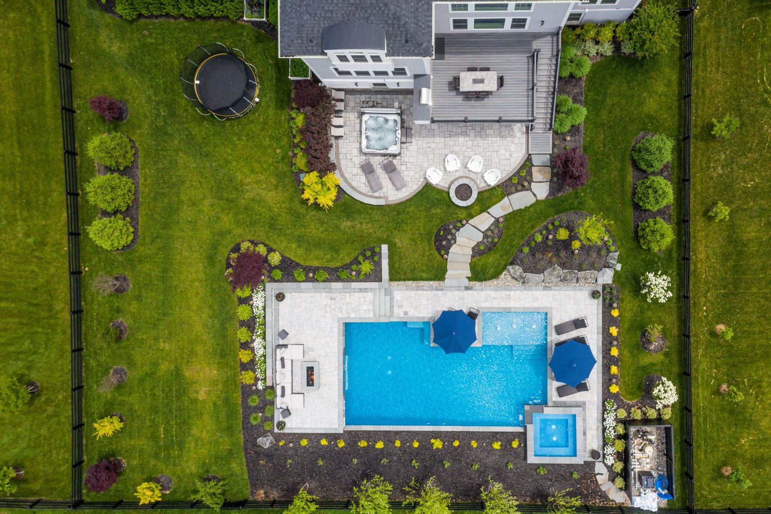 Birds-eye view of a backyard featuring rectangular pool surrounded by manicured landscaping.