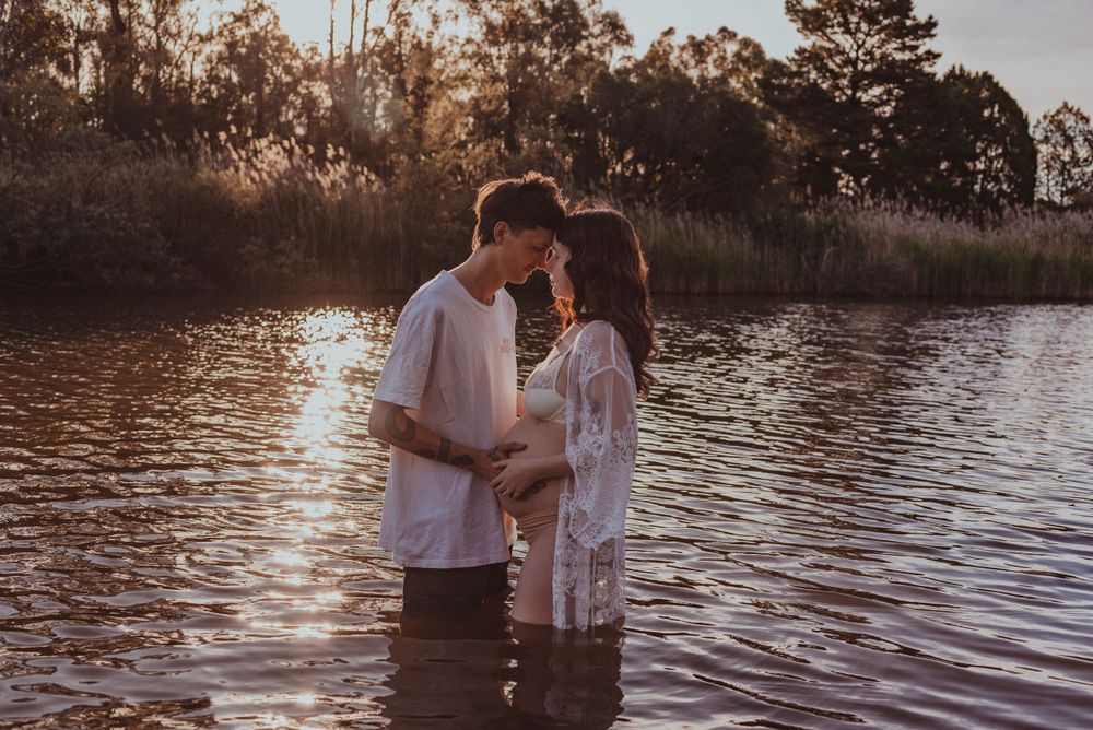 Romantic couple embracing in water during golden hour sunset.