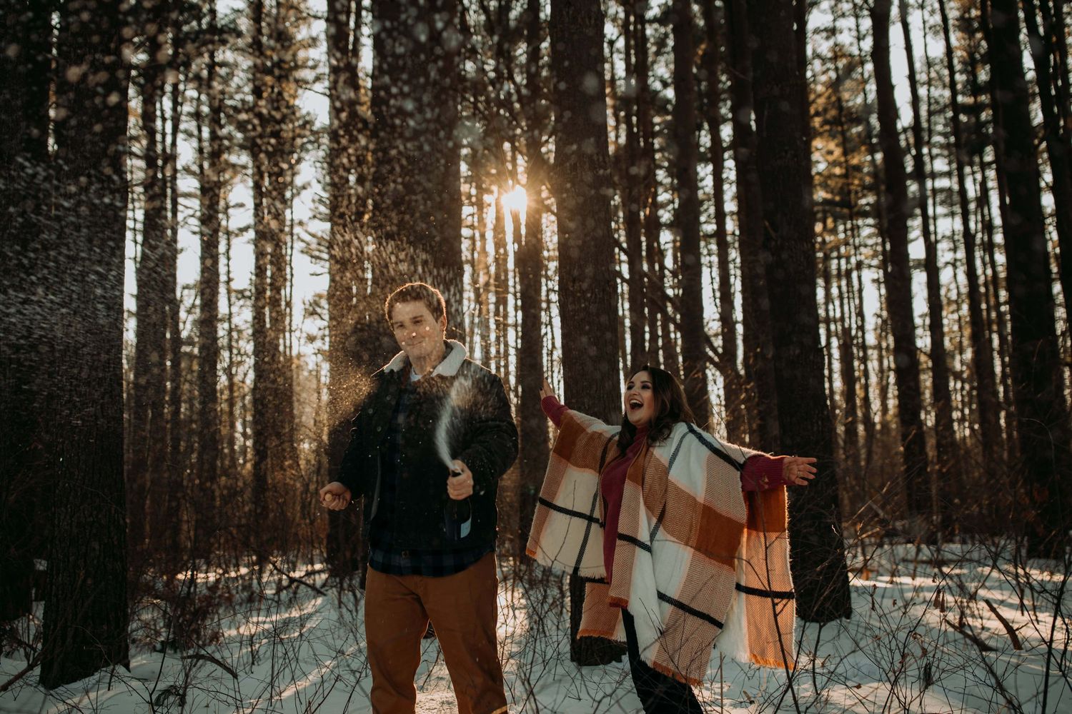 couple-popping-champagne-in-woods-in-snow