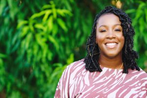 black female smiles hard in front of trees outside