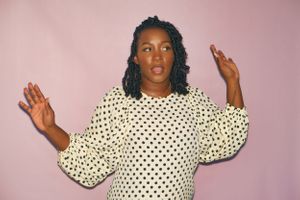 Black female poses in front of a pink backdrop