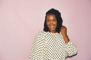 black female plays with her hair in front of pink backdrop