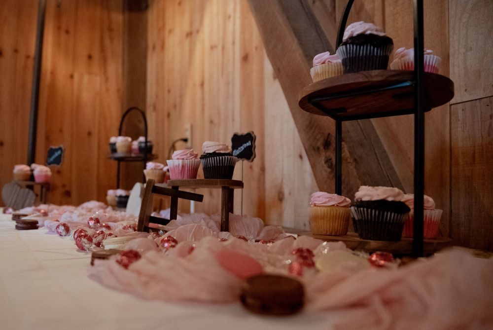 Multiple tiers of cupcakes arranged on wooden stands with pink fabric decoration.