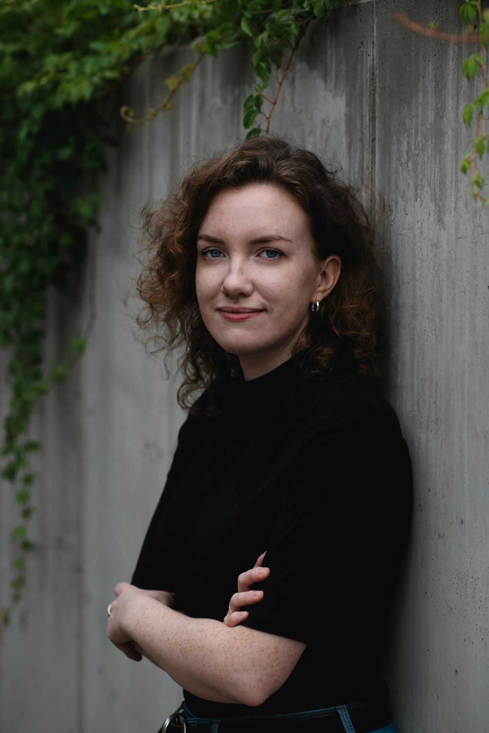 Portrait against a concrete wall with climbing ivy in natural lighting.