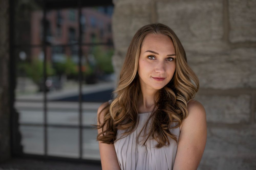 Professional headshot against a stone wall background in natural lighting.