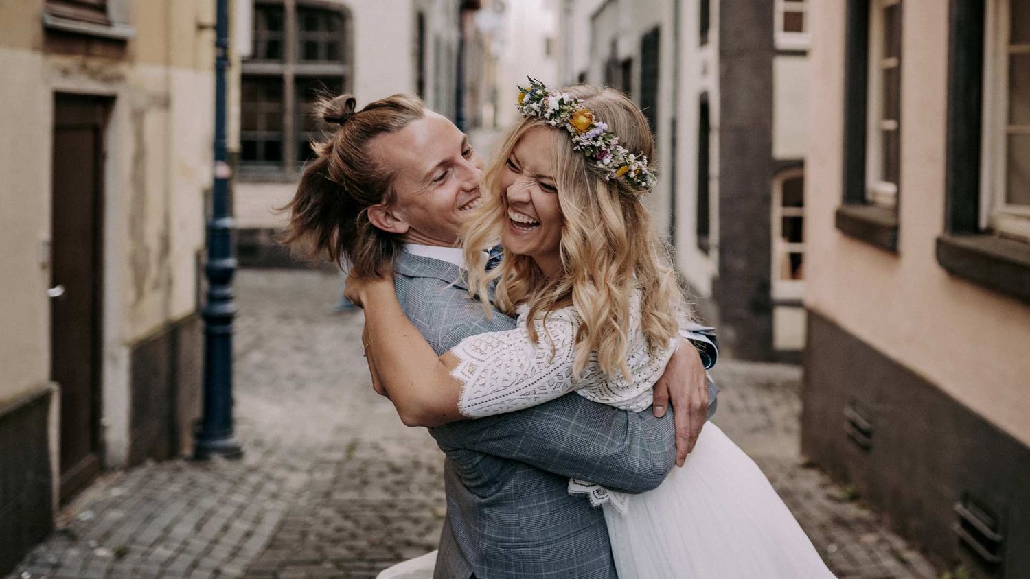 Wedding couple embraces and laughs together in a charming European alleyway.