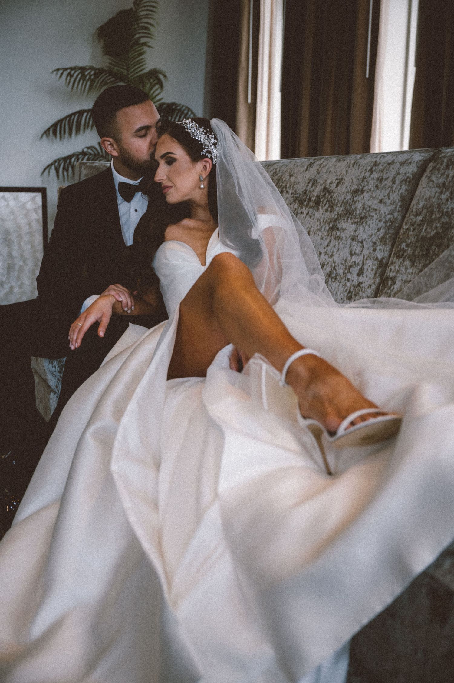 An intimate wedding portrait on a couch with dramatic lighting and flowing dress.