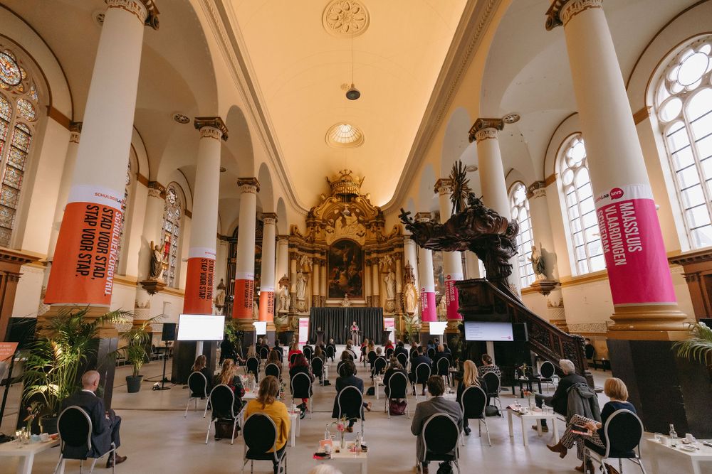 Interior of historic church converted into event space with white columns and colorful banners.