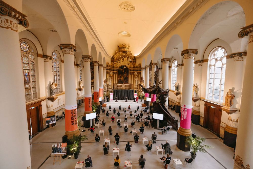 Aerial view of ornate church interior with socially distanced seating arrangements and decorative columns.