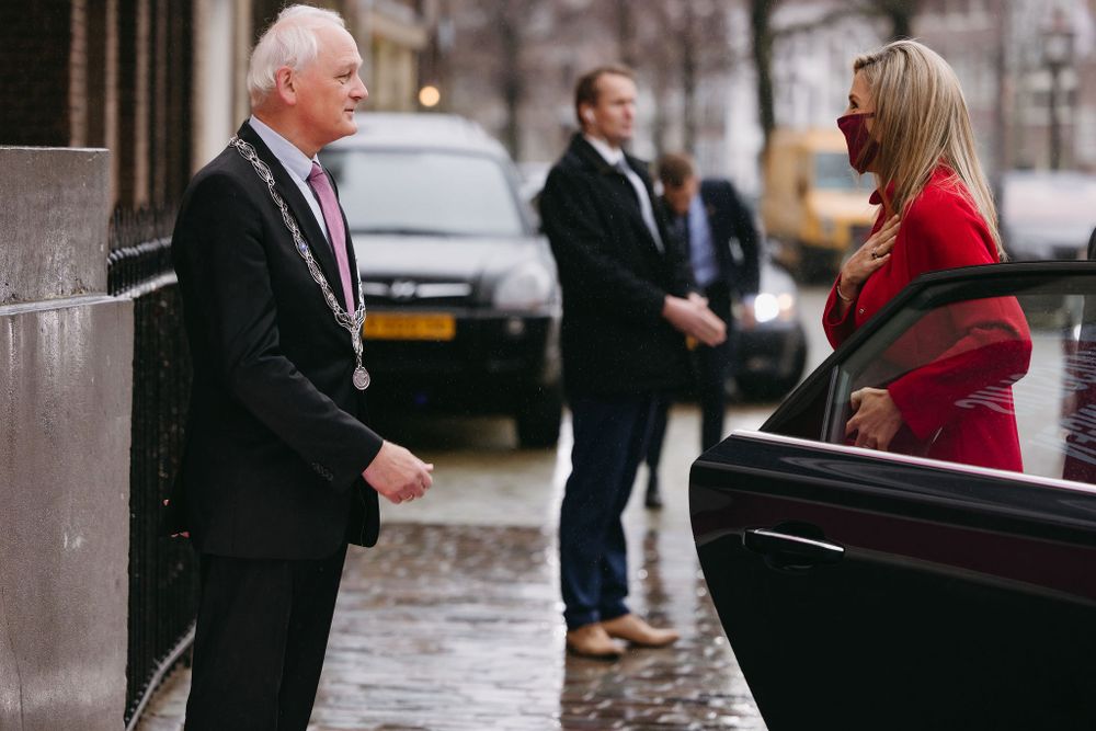 Professional interaction outside building on rainy day with car in background.