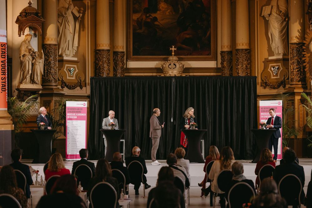 An elegant church interior hosts a presentation with black curtains and statues along the walls.