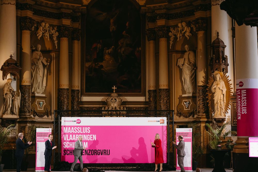A church interior features classical architecture with religious artwork and a modern pink stage setup.