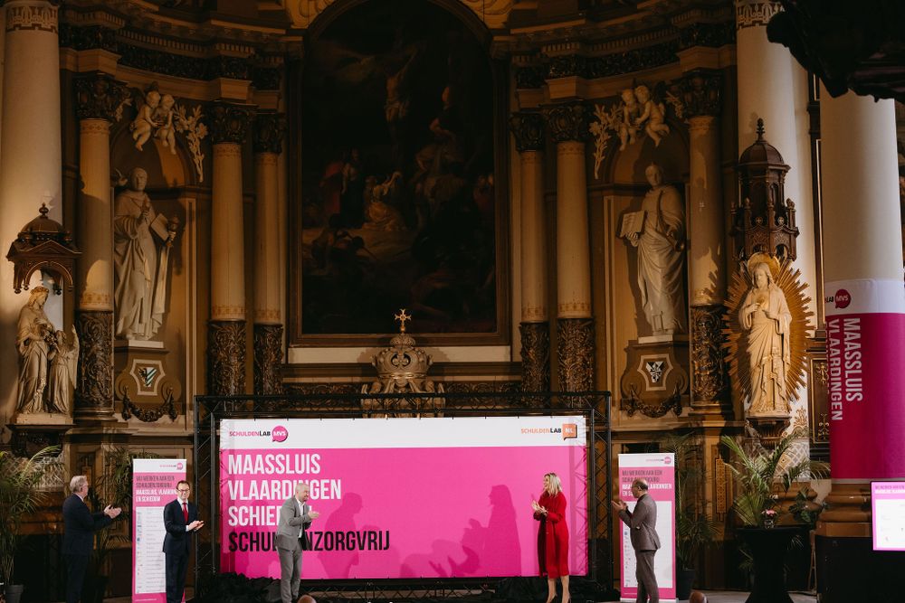 A church altar area transformed into a modern presentation space with pink signage and classical statues.