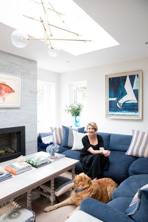 Modern living room featuring blue sectional, dog, and contemporary artwork with geometric light fixture during business branding photoshoot.