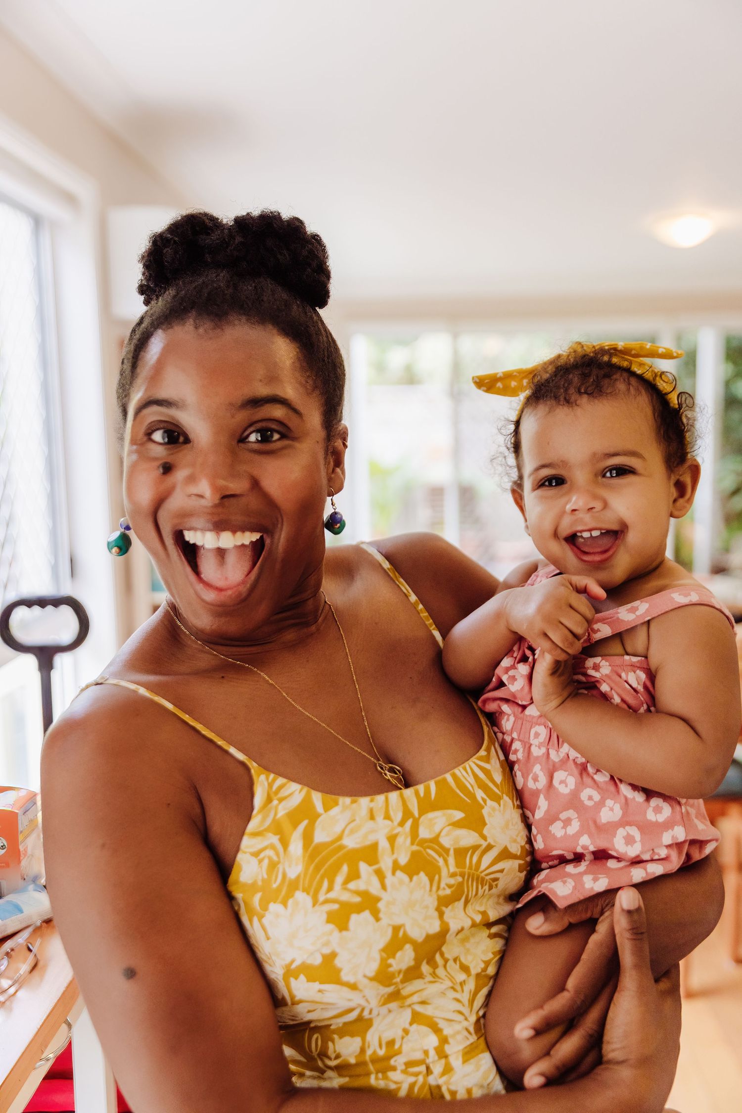 Mother and young daughter in matching yellow outfits sharing joyful expressions.