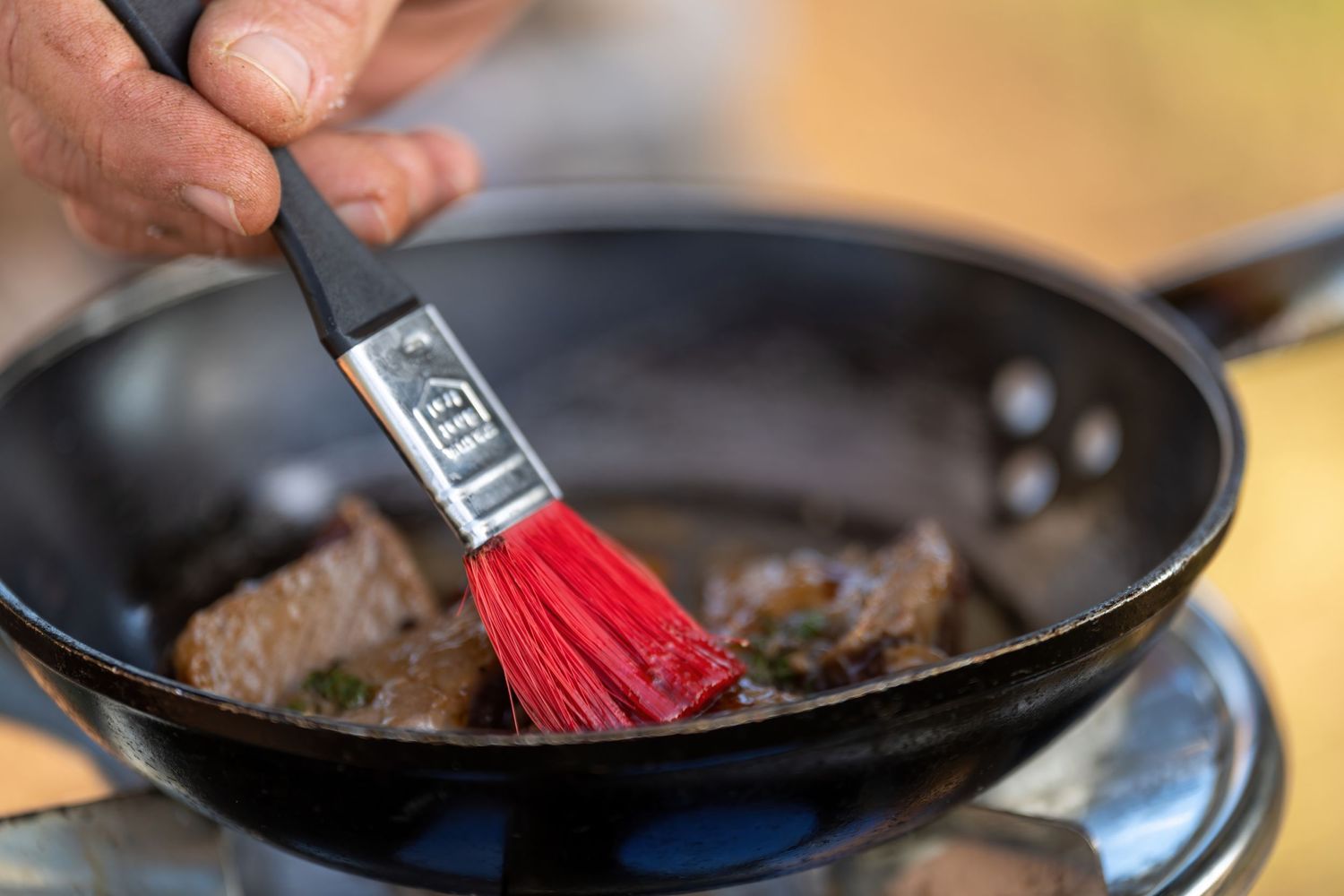 Cooking process showing meat being grilled in a cast iron pan.