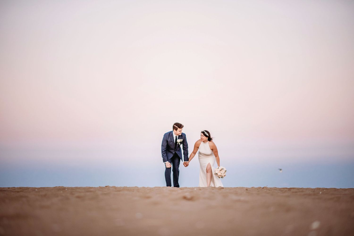 wedding photo of a couple running across a beach