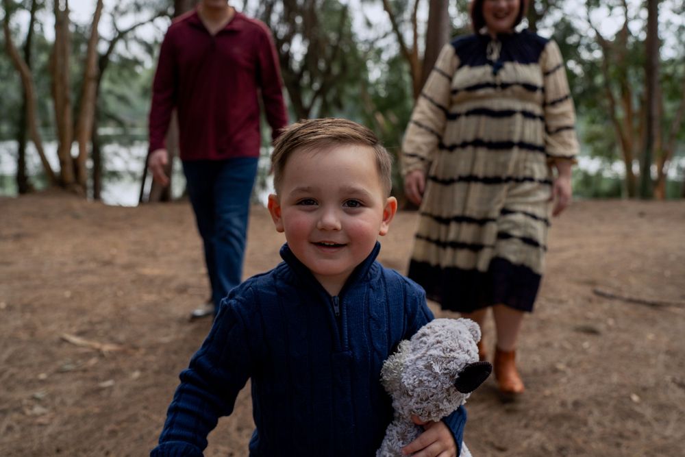 4 year old staring at camera with parents in the background
