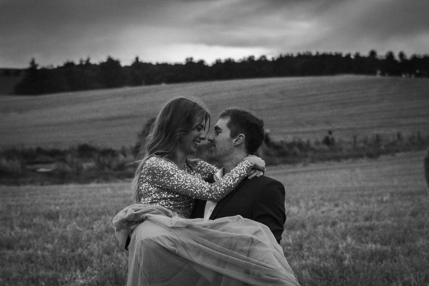 Man holding woman in his arms in the fields outside Dunnottar Castle.