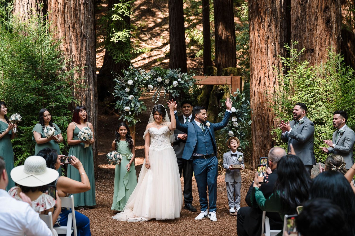 Guests capture photos of the newlyweds during a redwood forest wedding ceremony.