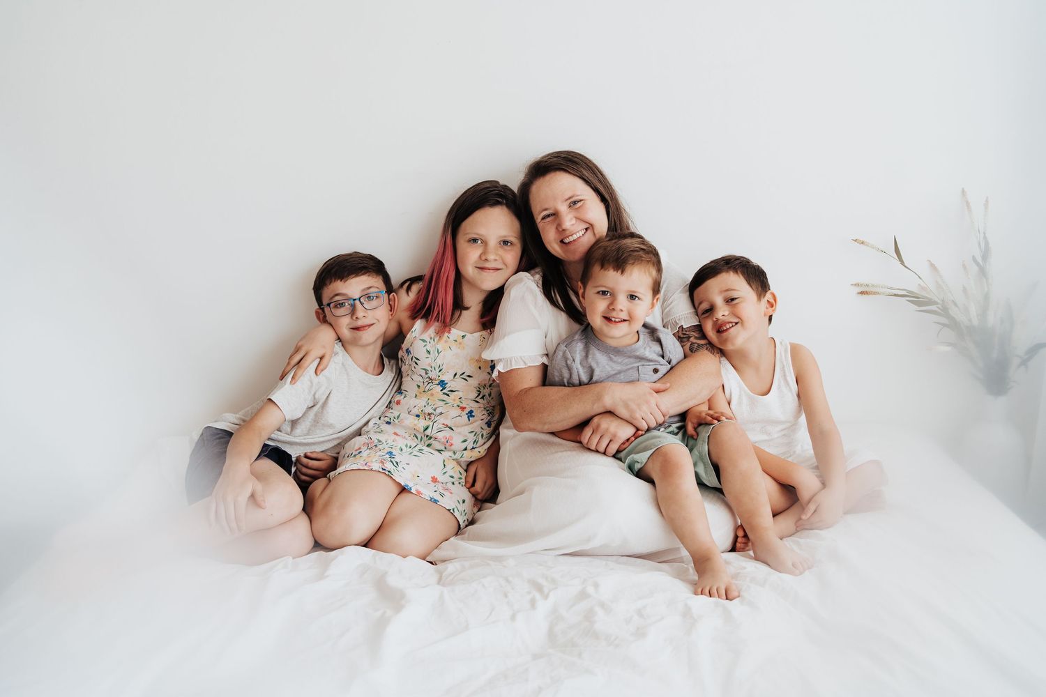 Family sitting on white blanket. Mother and four kids.
