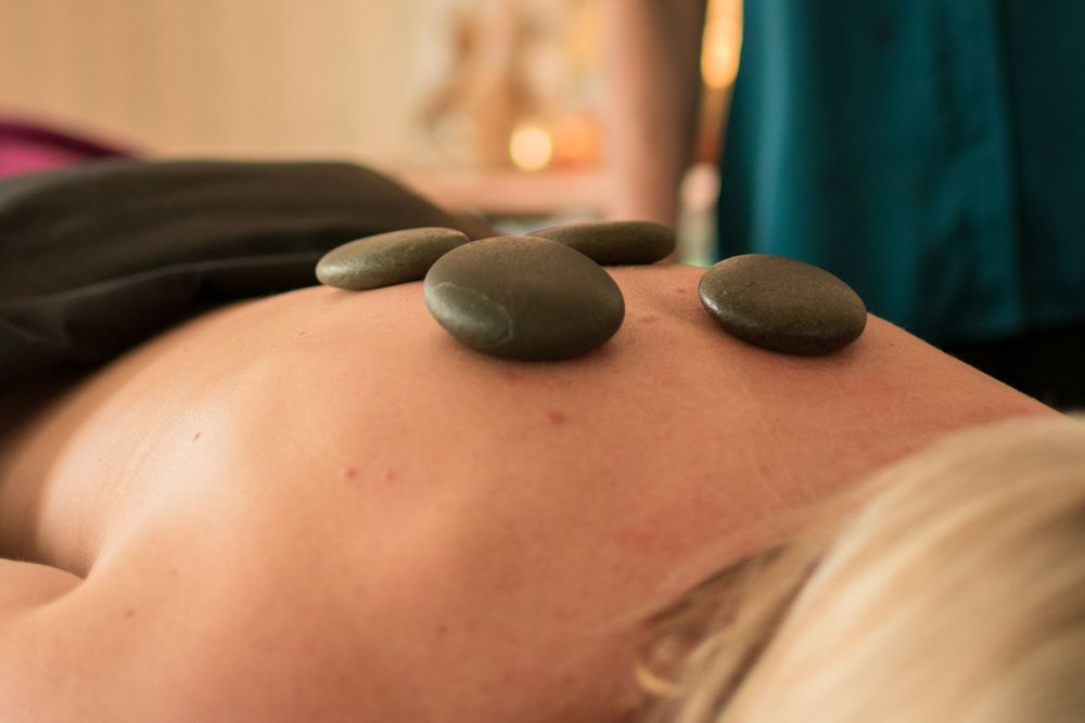 Close up photo of hot stones on a massage therapists client's back.