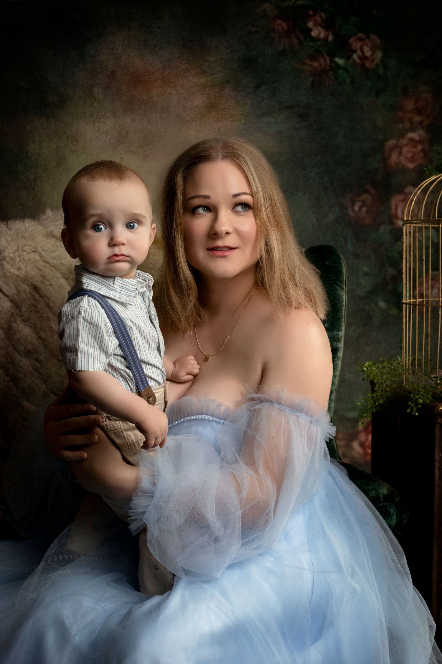 Ethereal family portrait with soft blue tulle dresses against a moody dark background.