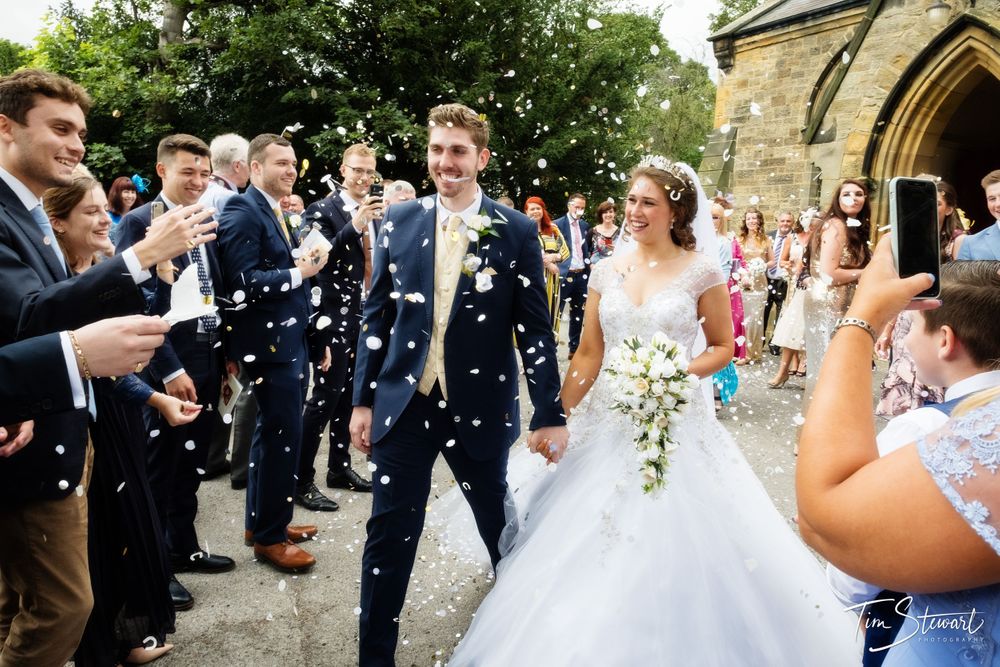 Guests throwing confetti over a bride and groom coming out of Christ Church, Great Ayton, North Yorkshire