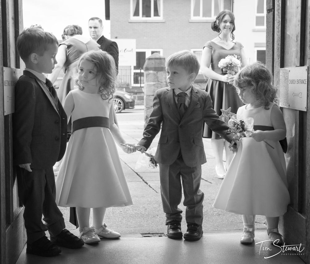 Flower girls and page boys holding hands in church doorway in Redcar