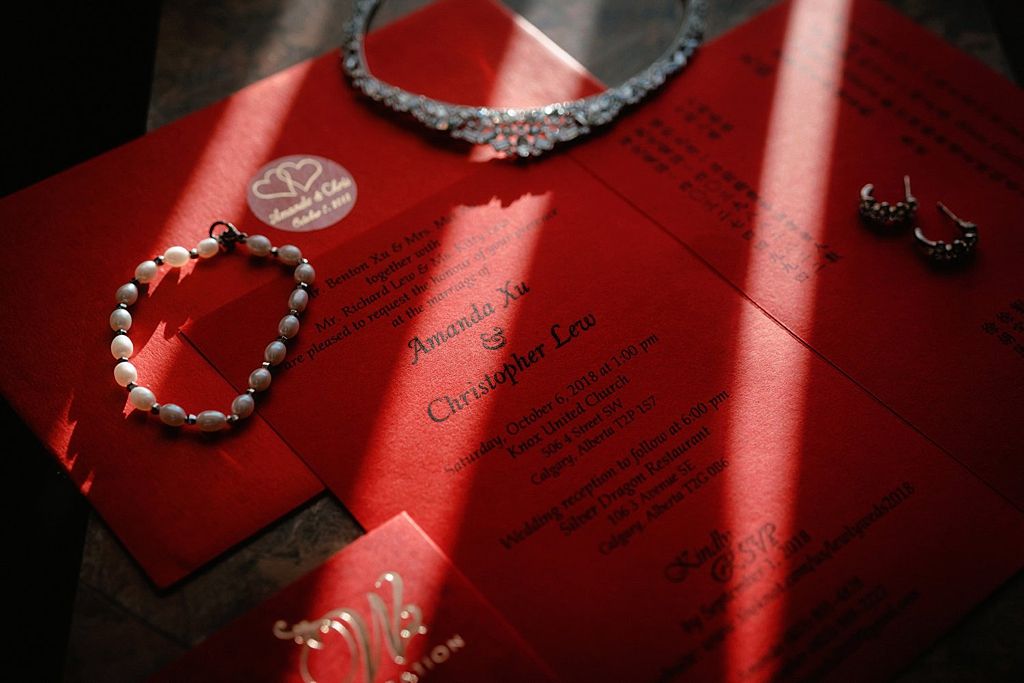 Wedding accessories and jewelry arranged on red paper in dramatic lighting.