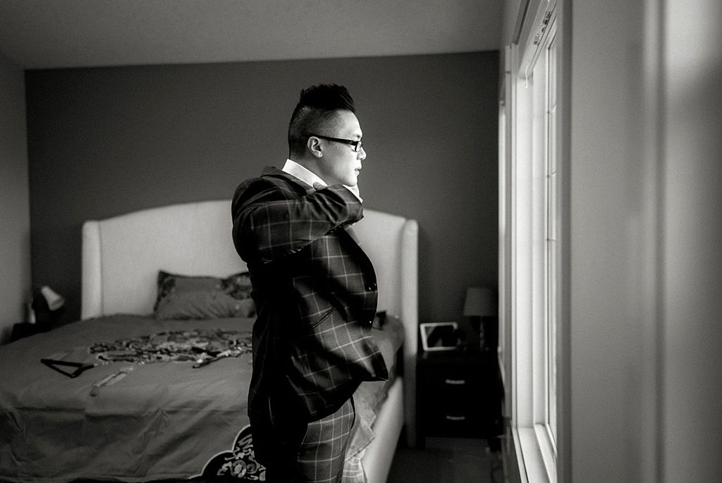 Black and white portrait near a window in formal attire.