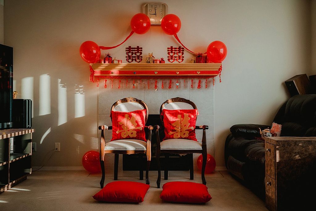 Chinese wedding ceremony setup with red balloons and traditional decorations in an indoor space.