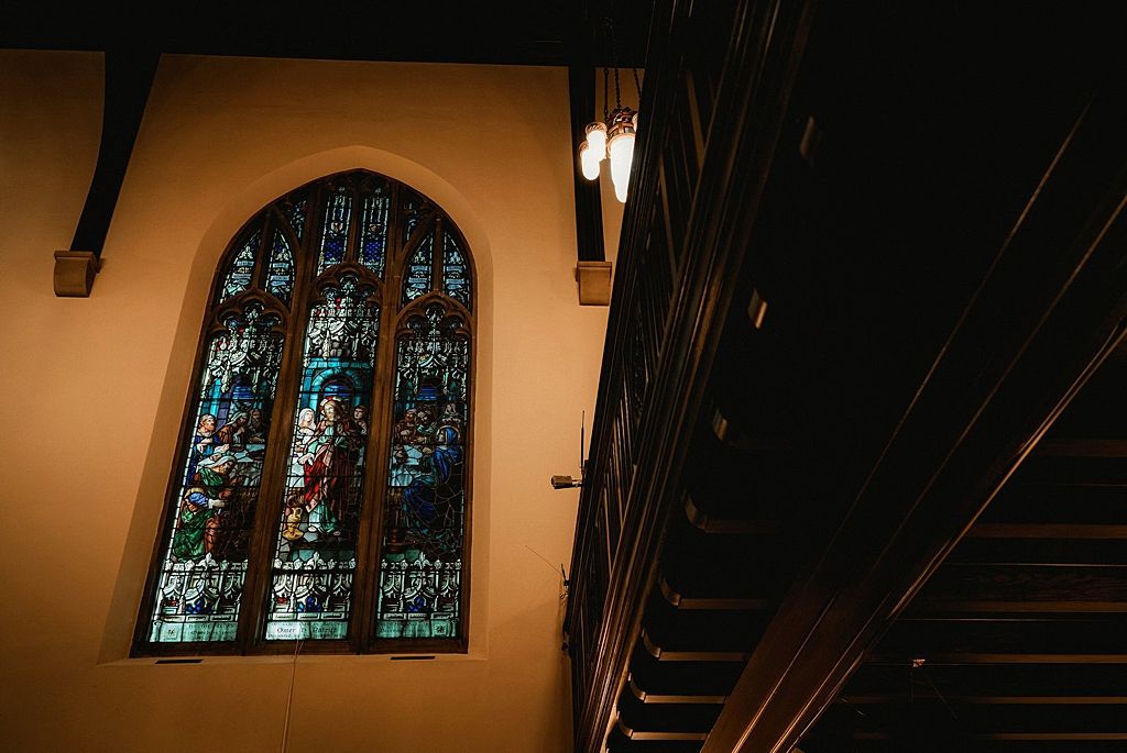 Dark interior of church or chapel with stained glass windows visible.