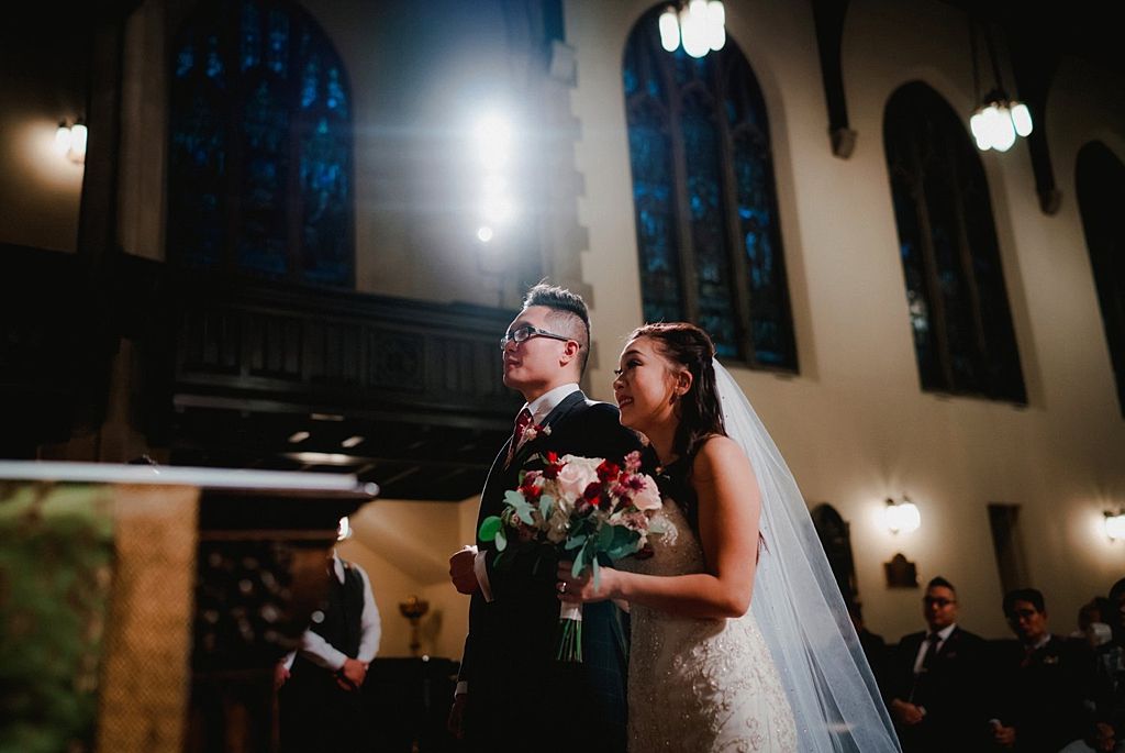 Wedding ceremony in a historic church with dramatic lighting and stained glass windows.