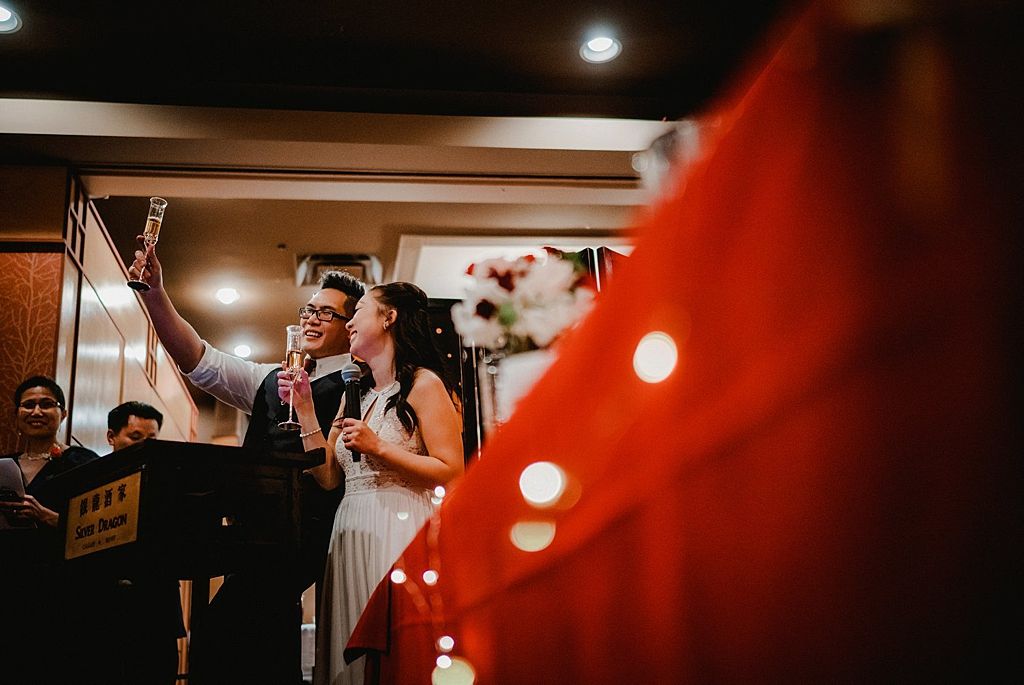 Wedding reception speeches with couple at microphone stand.