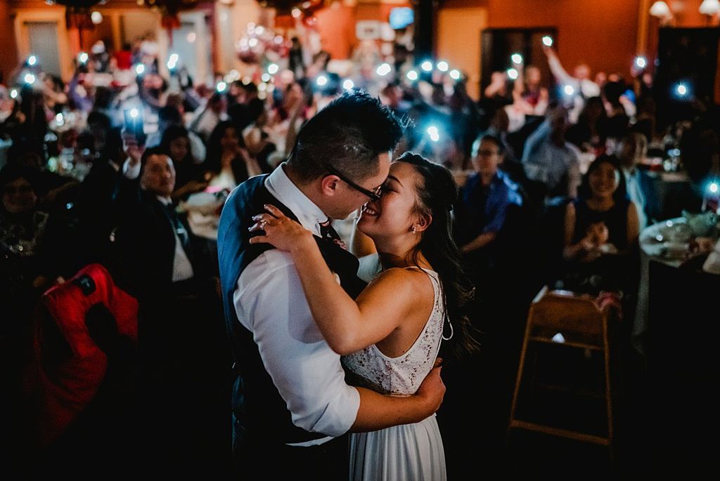 Romantic first dance moment at dimly lit wedding reception.